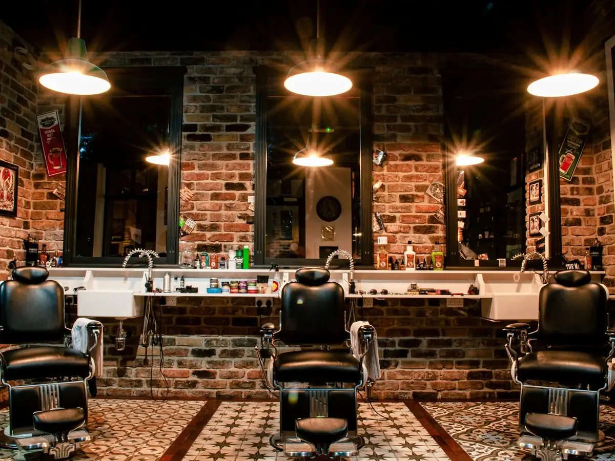A black leather barber chair beside a brick wall